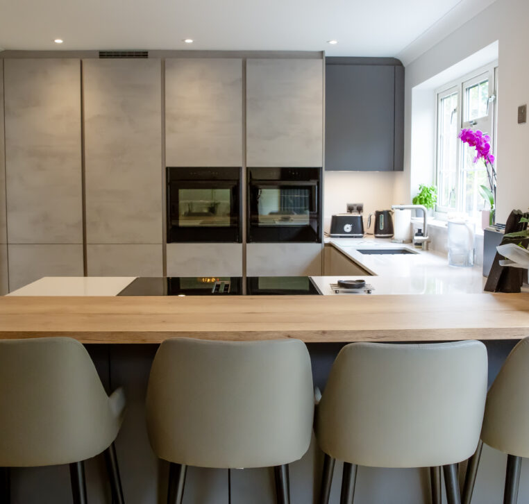 Modern kitchen with light grey cabinetry, a central island, and integrated cooktop.