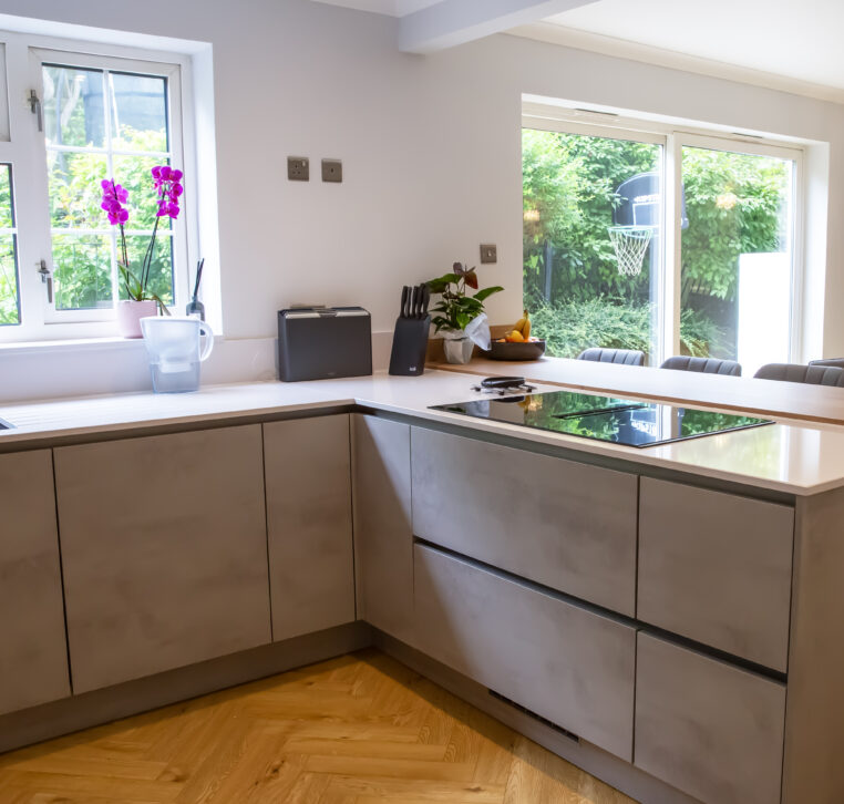 Modern kitchen with light grey cabinetry, a central island, and integrated cooktop.