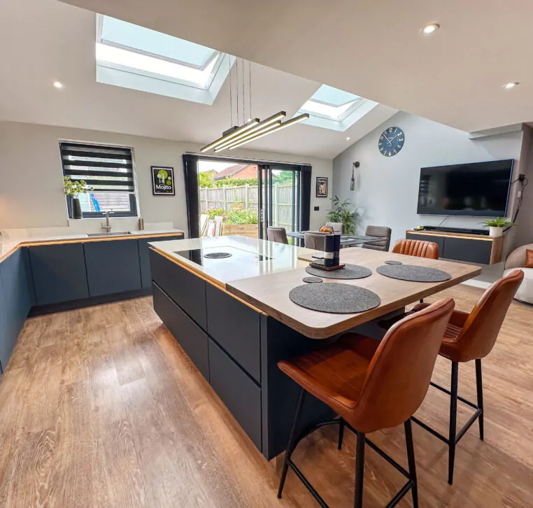 Image showing a modern kitchen with dark blue cabinetry, large island with induction hob, and skylights overhead.