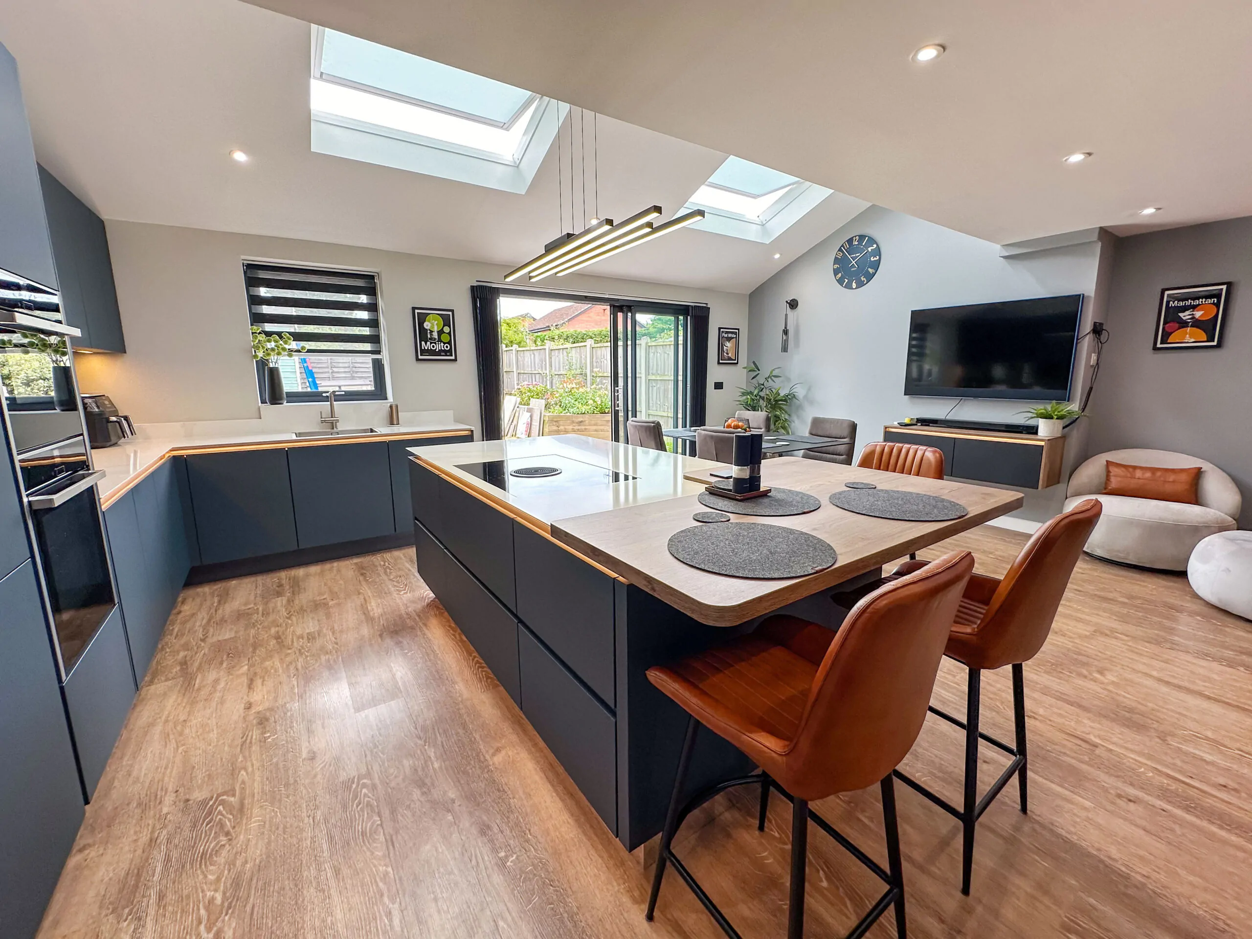Image showing a modern kitchen with dark blue cabinetry, large island with induction hob, and skylights overhead.