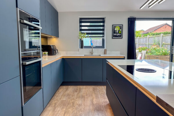 Modern kitchen showcasing a sleek design with dark cabinetry, white countertops, and oak breakfast bar.