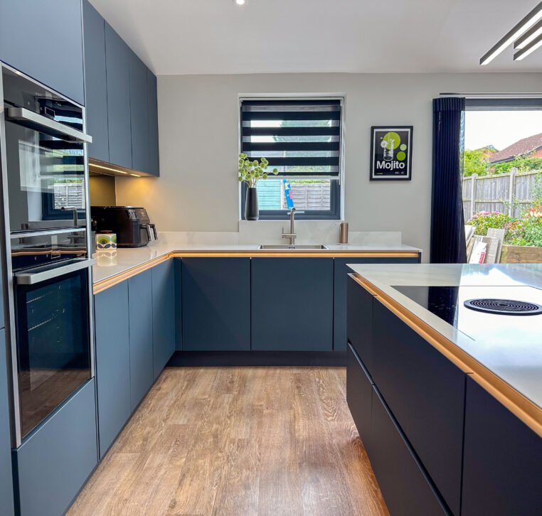 Modern kitchen showcasing a sleek design with dark cabinetry, white countertops, and oak breakfast bar.