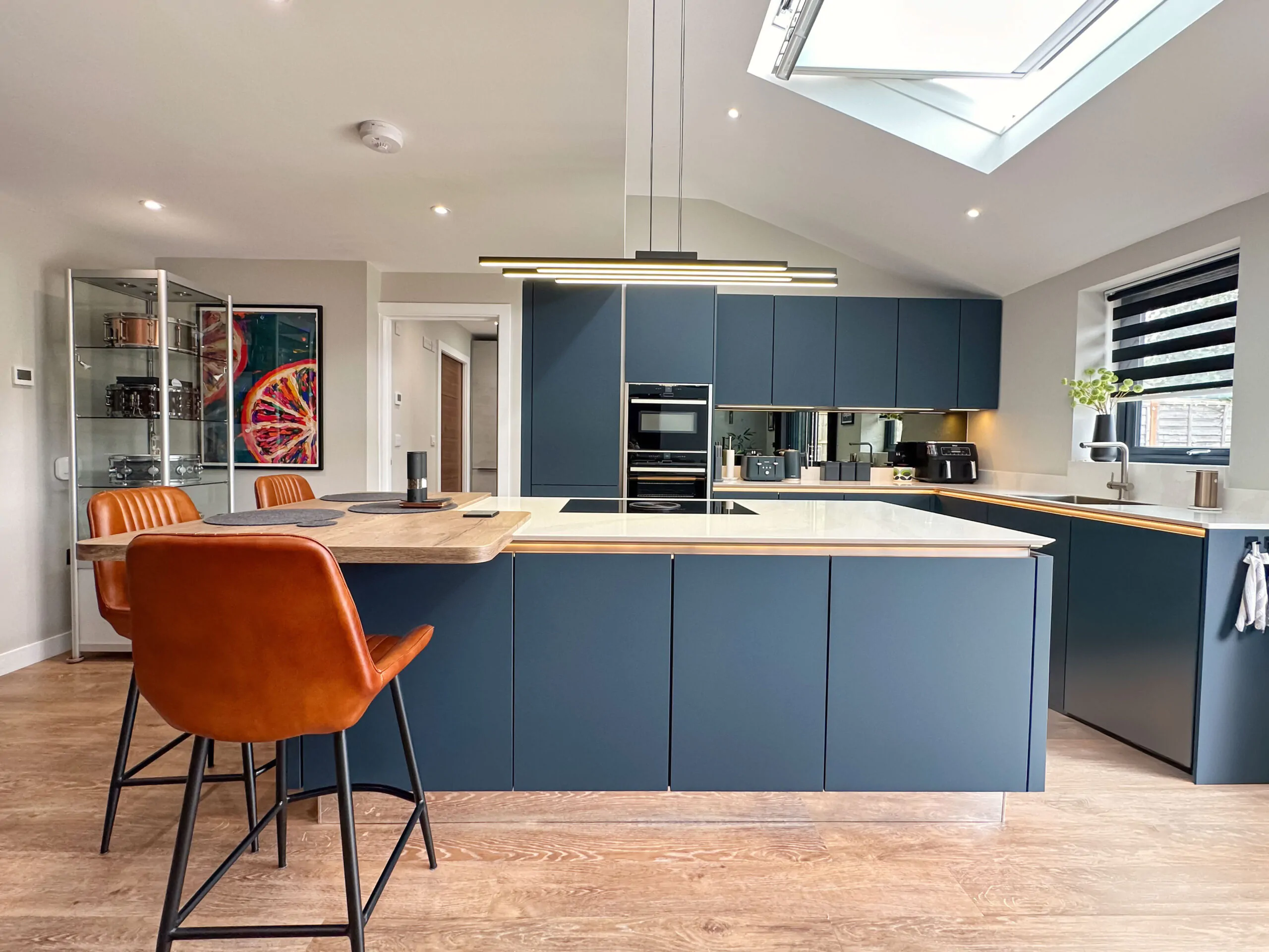 Modern kitchen showcasing a sleek design with dark cabinetry, white countertops, and oak breakfast bar.
