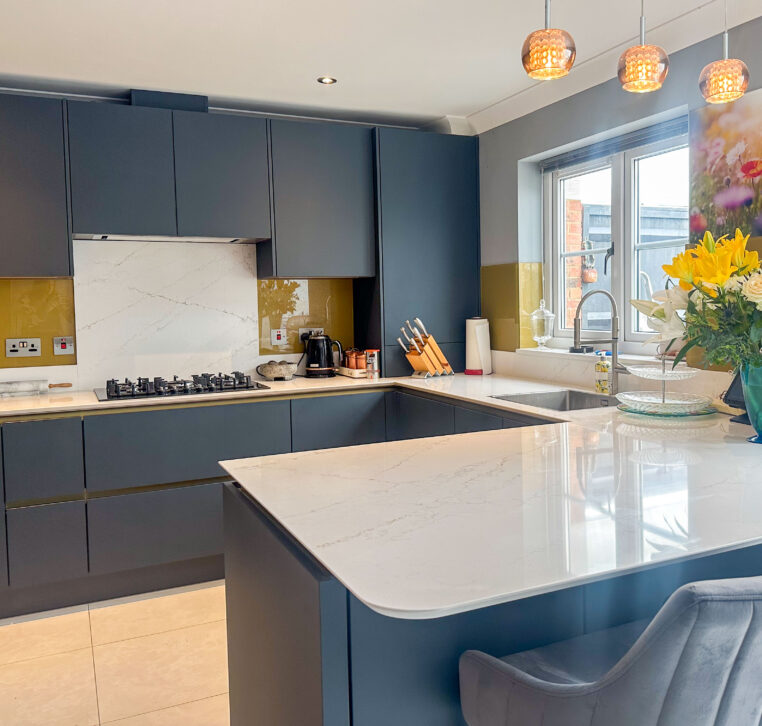 U-shaped kitchen with a peninsula, gold Line N cabinets, and quartz worktop.