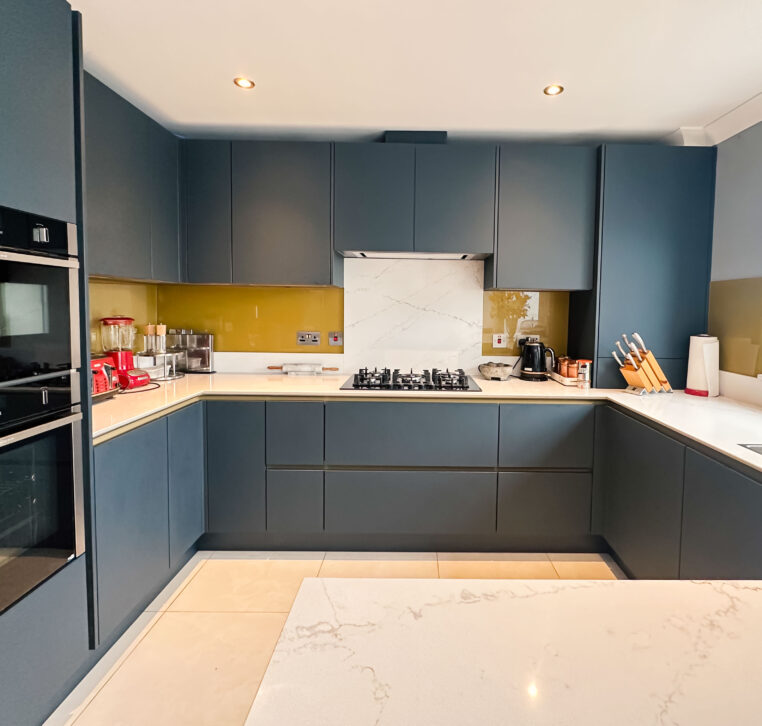 U-shaped kitchen with a peninsula, gold Line N cabinets, and quartz worktop.