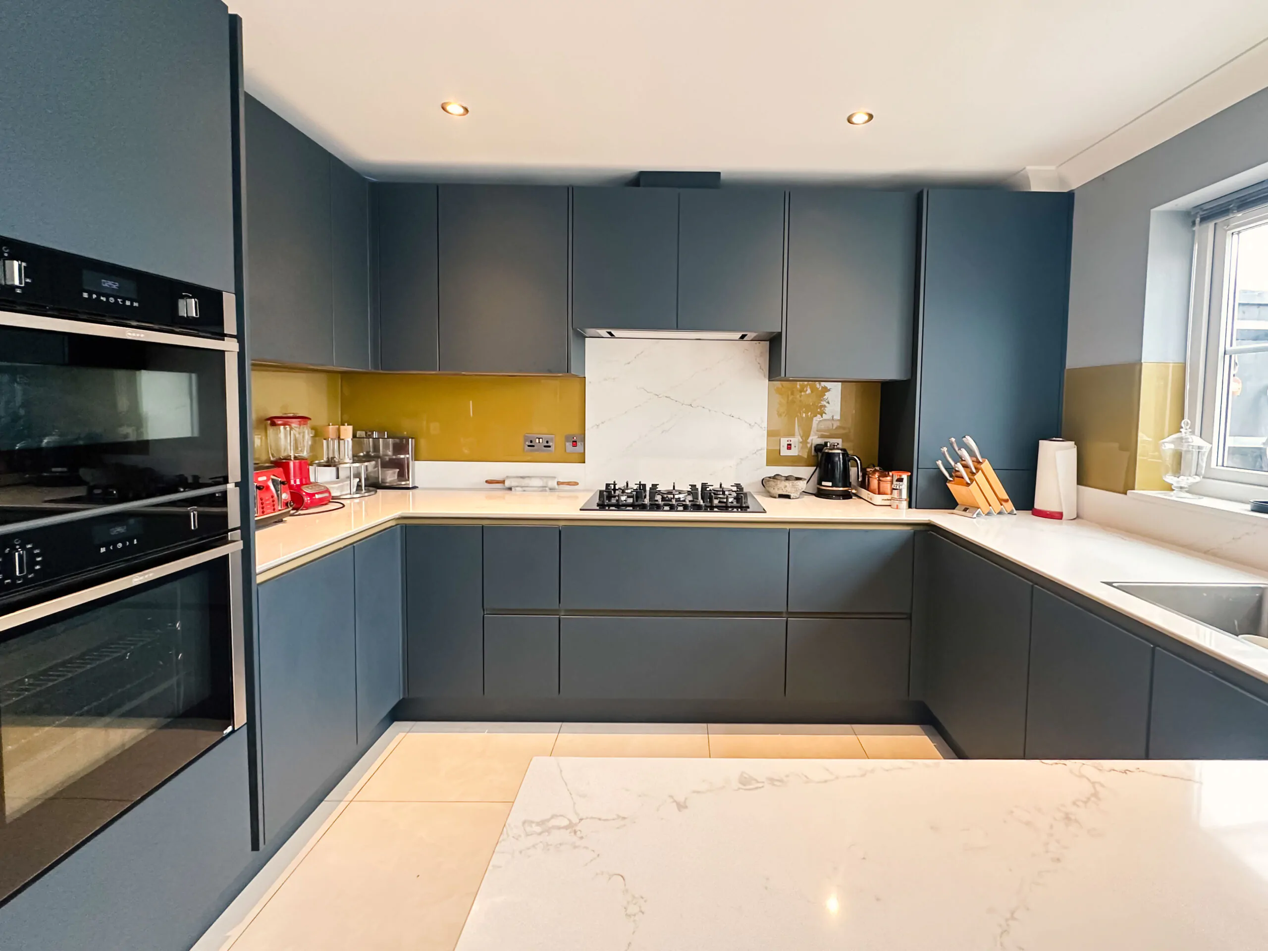 U-shaped kitchen with a peninsula, gold Line N cabinets, and quartz worktop.