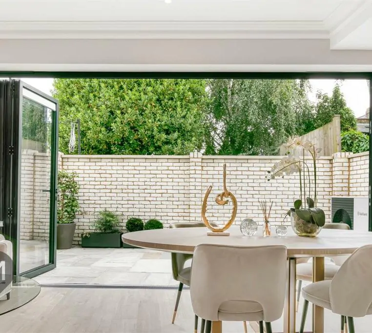 View from the dining table towards the outdoor courtyard through floor-to-ceiling glass doors in a Camborne Mews home