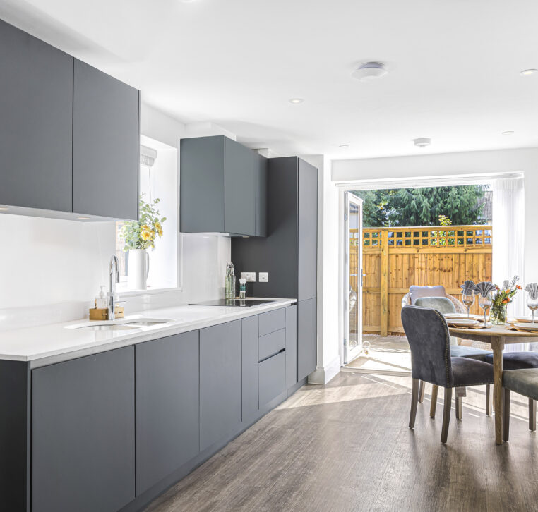 Open-plan kitchen and dining area with modern cabinetry, wooden flooring, and natural light