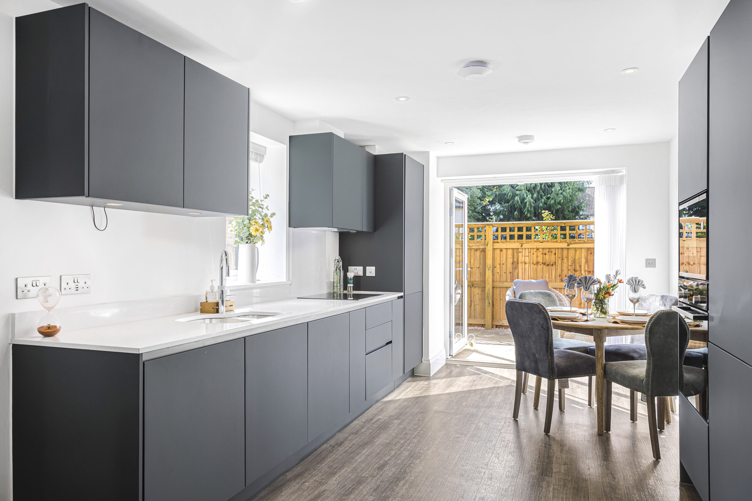 Open-plan kitchen and dining area with modern cabinetry, wooden flooring, and natural light