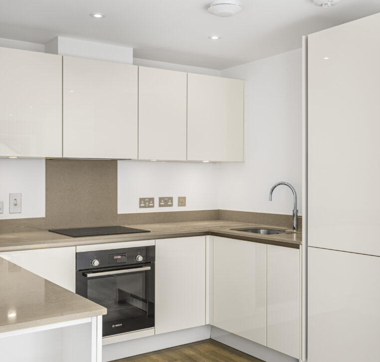 Modern white kitchen with built-in oven, minimalist design, and U-shaped layout in Reading new-build