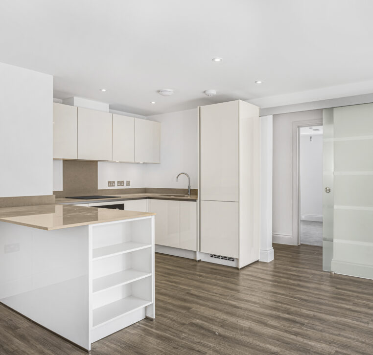 Modern white kitchen with integrated appliances, sleek worktops, and ample storage in Reading property development