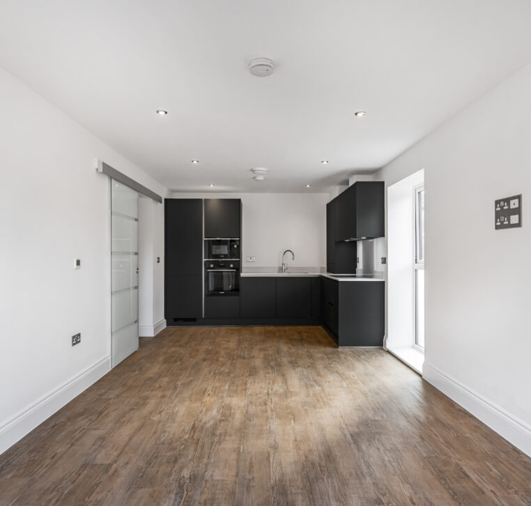 Spacious open-plan kitchen with dark grey cabinets and wood-effect flooring in Alton new-build