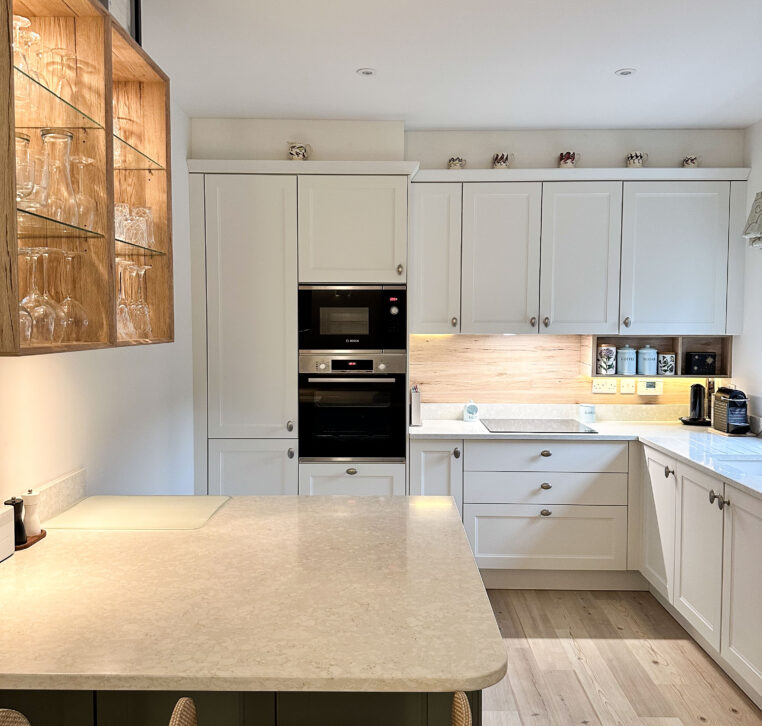 Open-plan shaker kitchen with green and white cabinetry and new wall opening