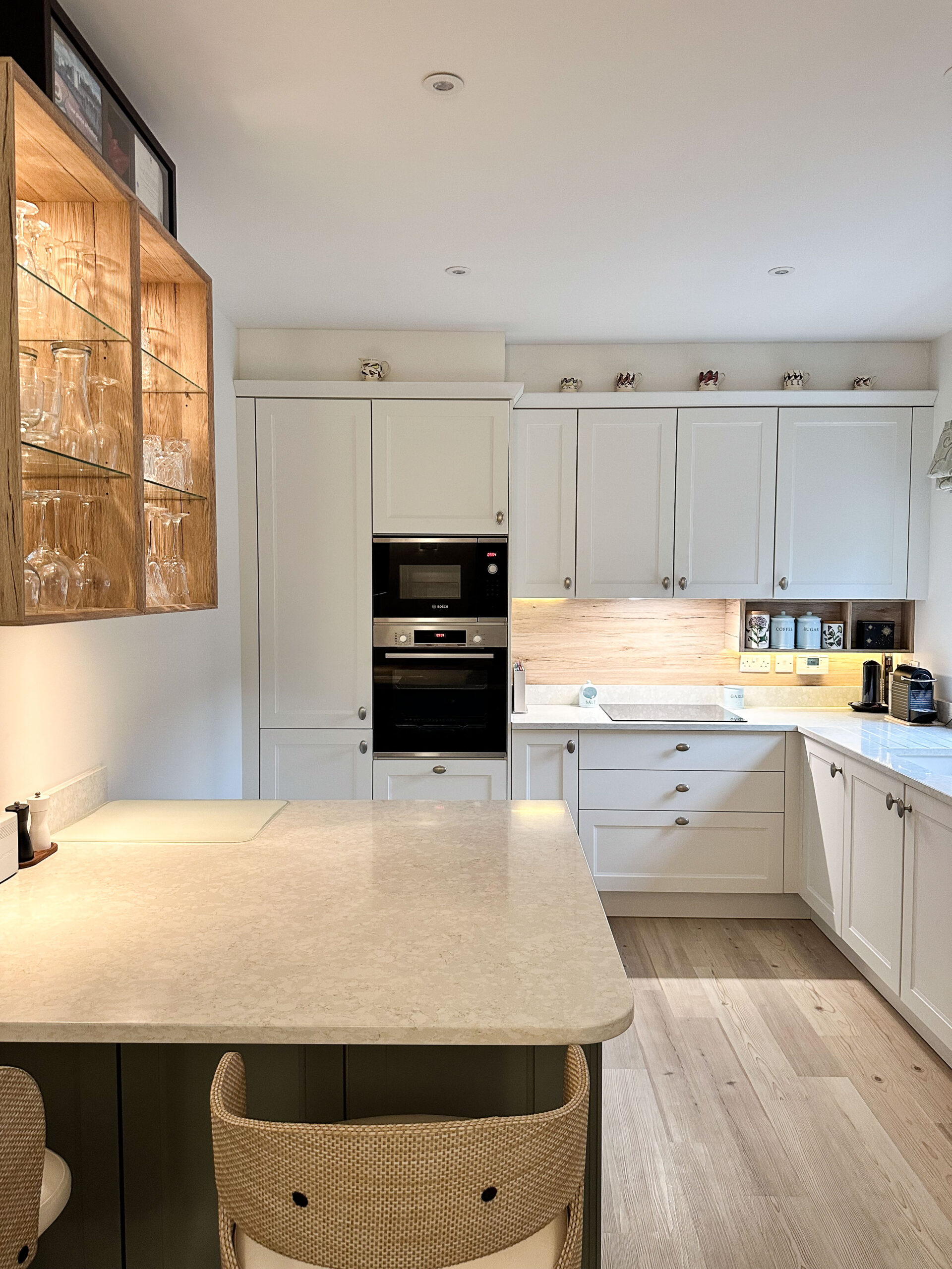 Open-plan shaker kitchen with green and white cabinetry and new wall opening