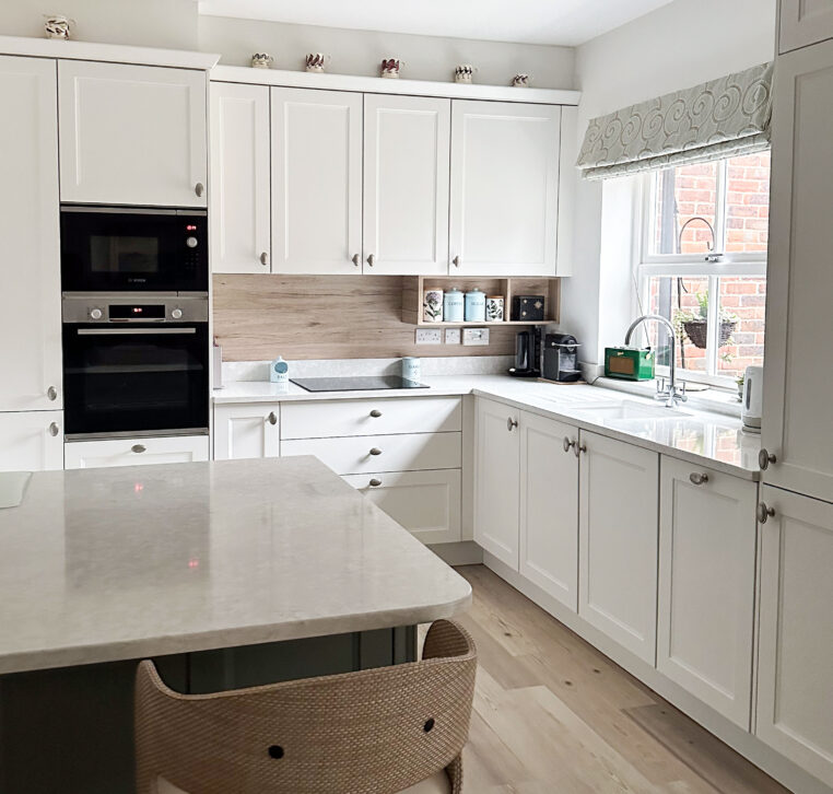 Elegant shaker cabinets in green and white with polished quartz worktop