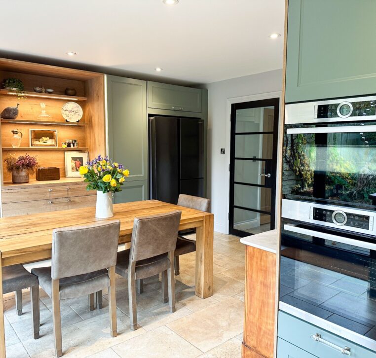 Rustic dining area in a wood shaker kitchen with bi-fold doors leading to a garden