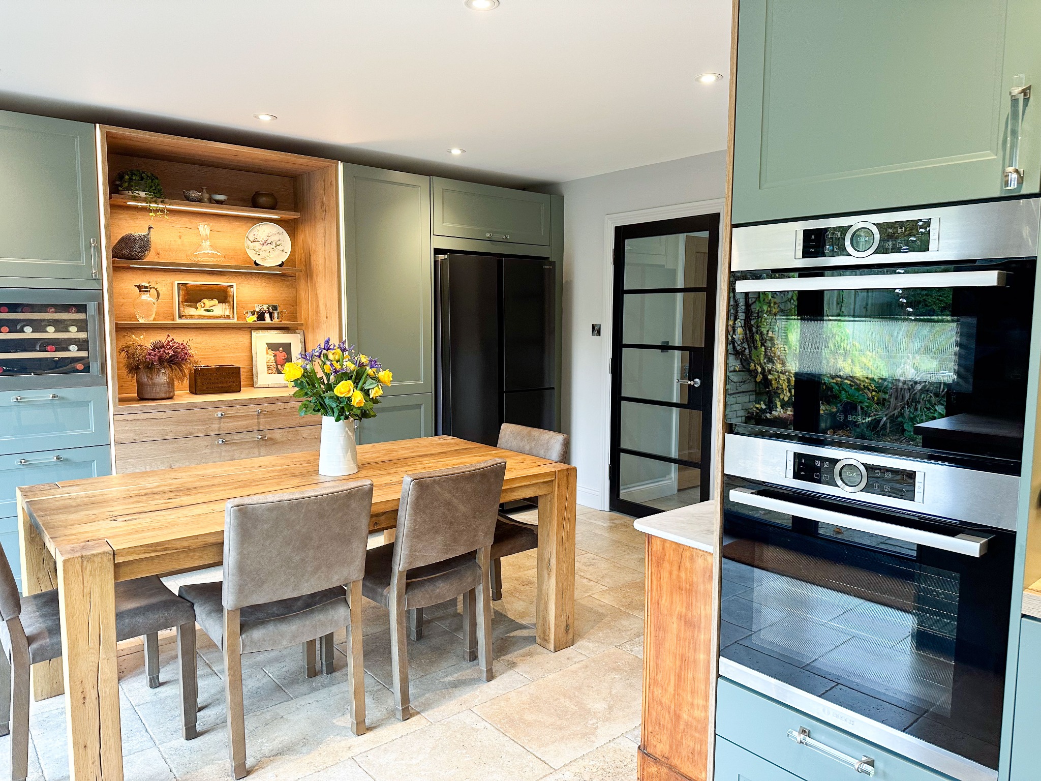 Rustic dining area in a wood shaker kitchen with bi-fold doors leading to a garden