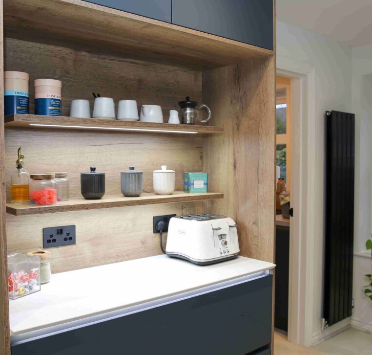 Kitchen coffee station with wooden shelving, navy cabinetry, and a white marble countertop featuring a toaster and decorative jars