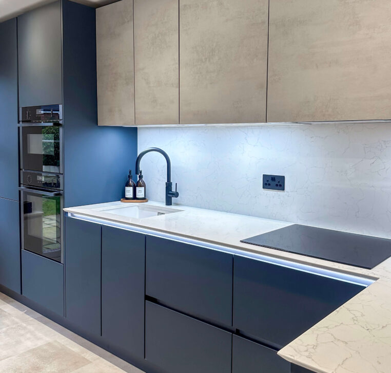 Contemporary kitchen with navy blue lower cabinets, grey upper cabinets, white marble countertops, and a modern black tap
