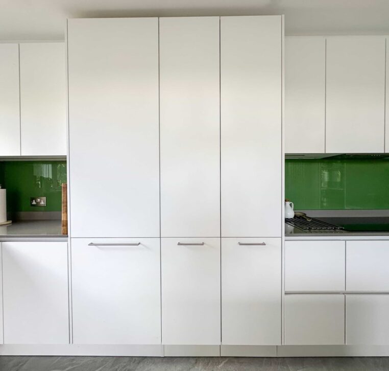 A modern kitchen with a grey countertop island, light fabric bar stools, and dark grey tiled flooring.