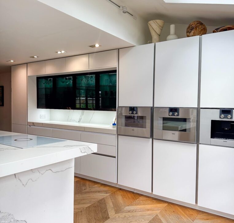 A sleek kitchen design with a white marble island, grey upholstered bar stools, and industrial-style pendant lights.