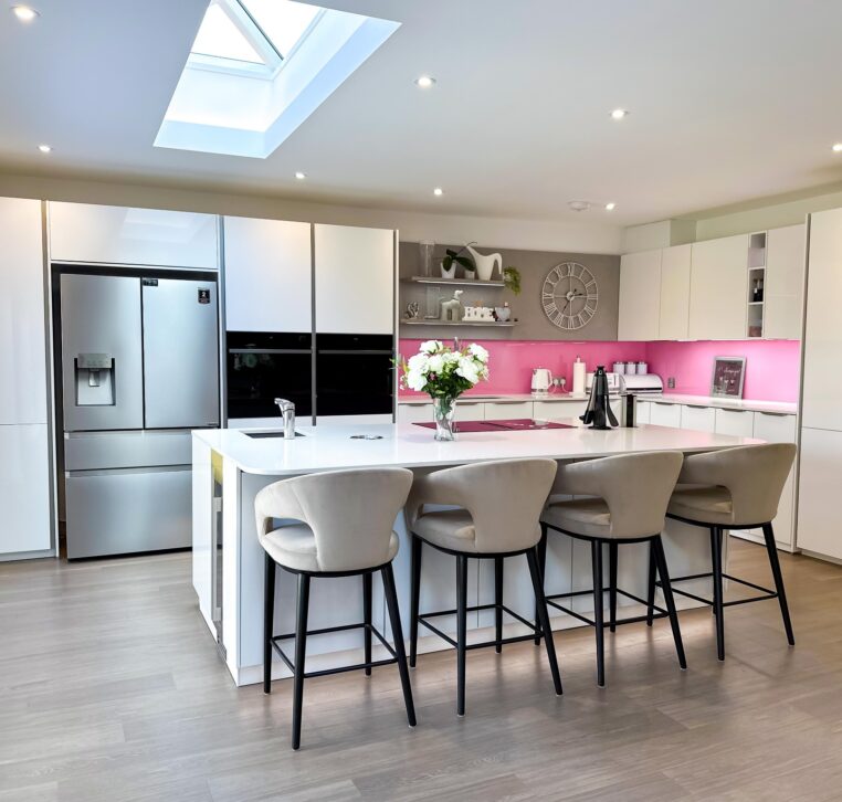 Close-up of a modern kitchen white island featuring a black sink and chrome faucet under recessed lighting.