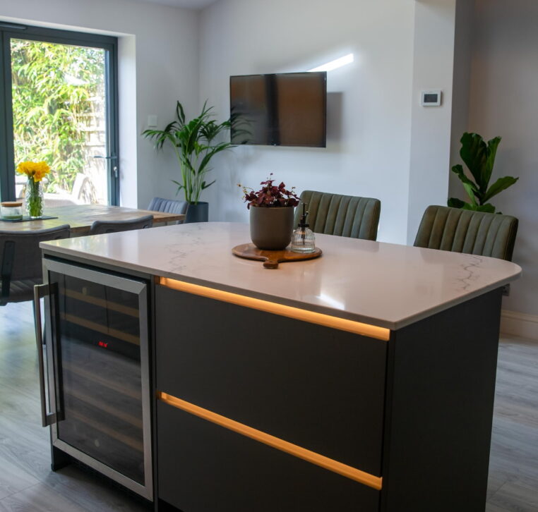 Luxury grey kitchen with modern pendant lighting, island seating, and rustic wood dining table.
