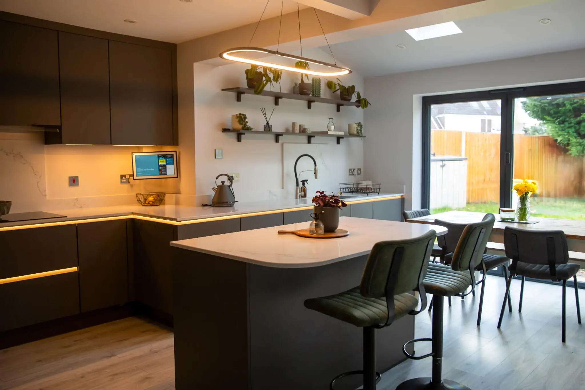Stylish grey kitchen diner with skylights, pendant lighting, and sliding doors to the garden.