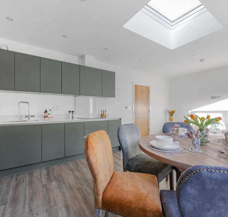 Bright dining area with round wooden table and colourful chairs