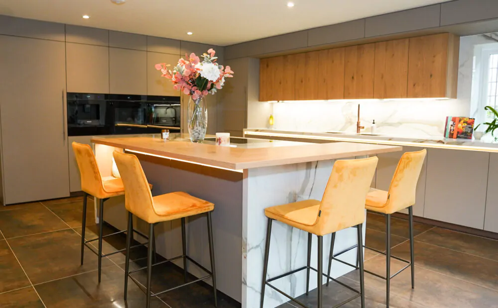 Modern handleless kitchen with marble waterfall island and grey cabinetry.
