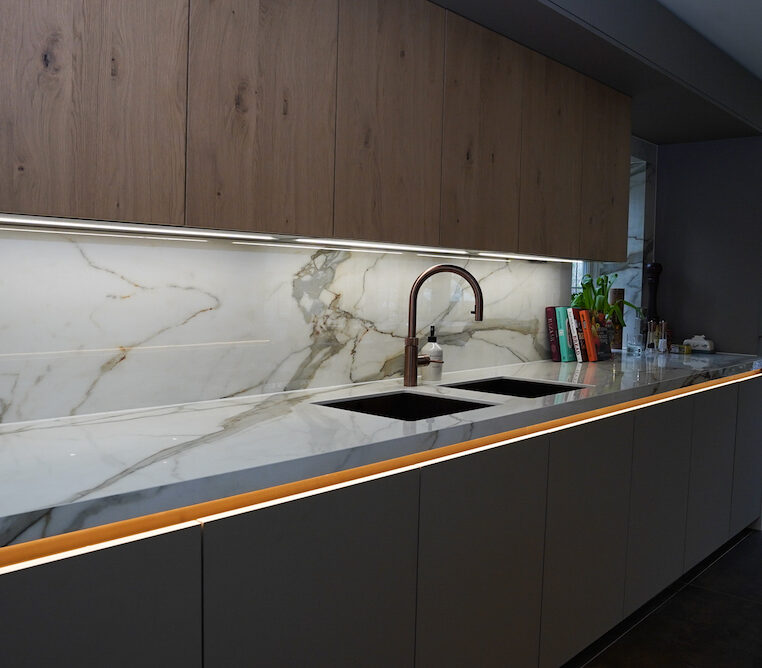 Marble splashback with integrated sink and bronze kitchen tap.