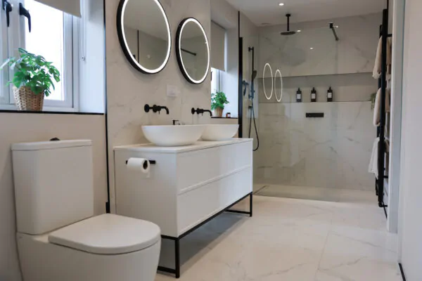 Modern bathroom with double vanity, wall-mounted taps, and walk-in shower.