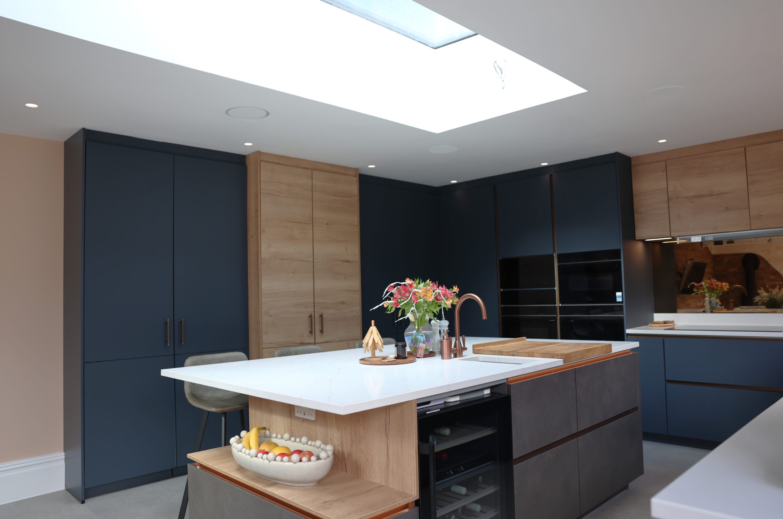 Handleless kitchen with dark blue cabinets, wood panelling and large central island