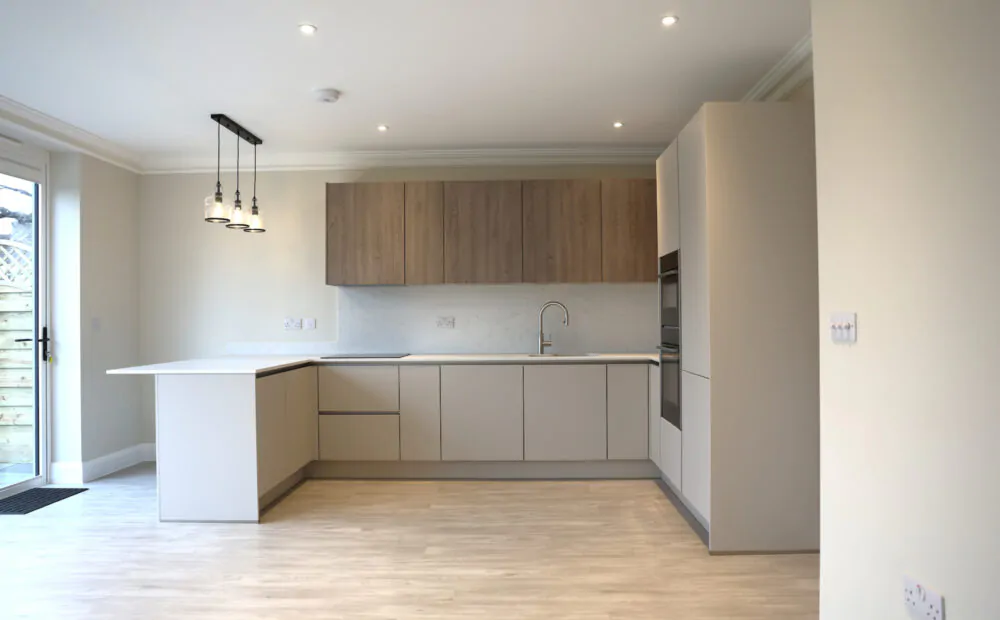 Open plan kitchen installation in Reading featuring handleless cabinetry, wood wall units and integrated appliances