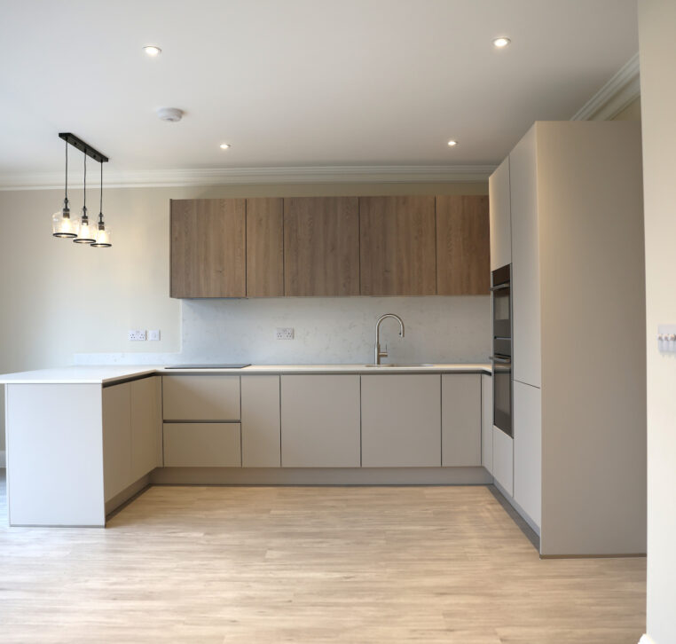 Open plan kitchen installation in Reading featuring handleless cabinetry, wood wall units and integrated appliances