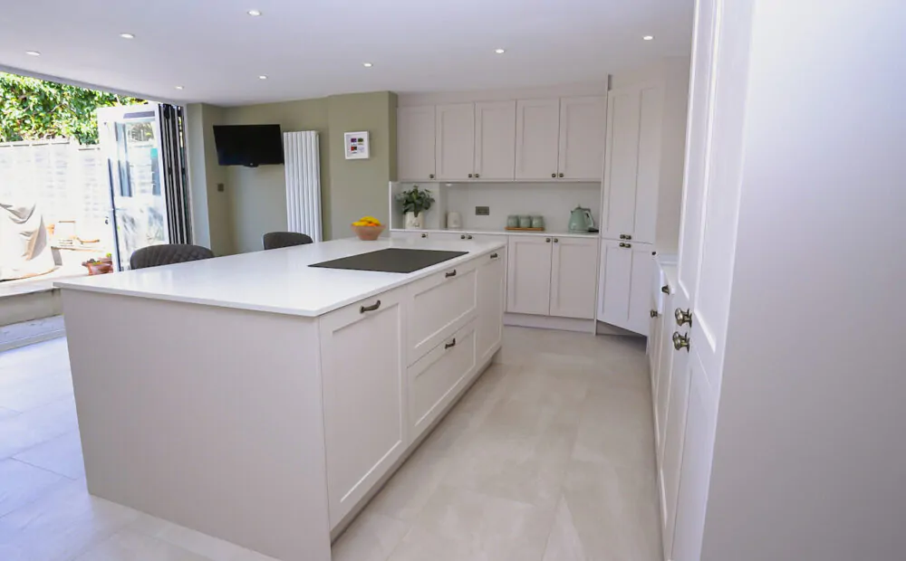 Open-plan shaker kitchen with large island and bifold doors creating a bright family living space.