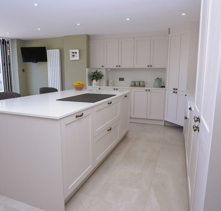 Open-plan shaker kitchen with large island and bifold doors creating a bright family living space.