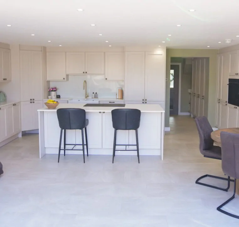 Open-plan shaker kitchen with central island seating and soft neutral cabinetry designed by MAS Collection.